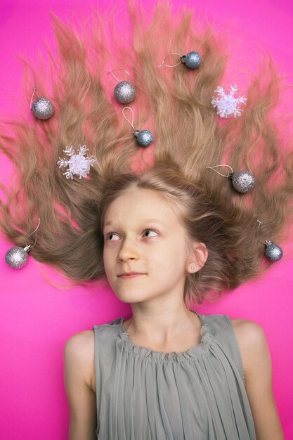 Des vacances folles, heureuses et lumineuses du Nouvel An. fille avec des boules de noël sur fond rose