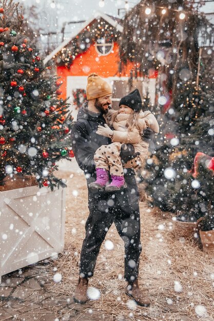 Vacances d'hiver et concept populaire famille heureuse avec petite fille choisissant l'arbre de Noël