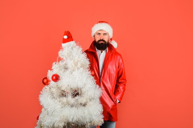 Vacances d'hiver noël ou nouvel an homme d'affaires barbu en bonnet de noel tient l'arbre de noël heureux