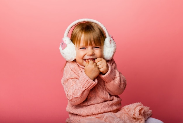 Vacances d'hiver. Petite fille écoute de la musique dans des écouteurs d'hiver. Fille en vêtements d'hiver.