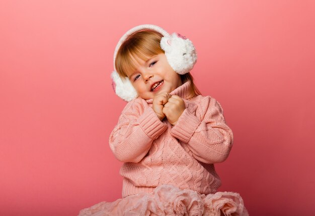 Vacances d'hiver. Petite fille écoute de la musique dans des écouteurs d'hiver. Fille en vêtements d'hiver.