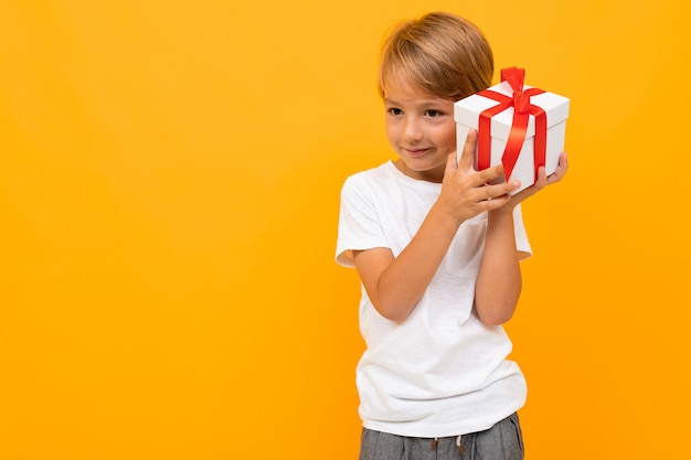 Vacances . joli garçon avec boîte-cadeau sur jaune vif