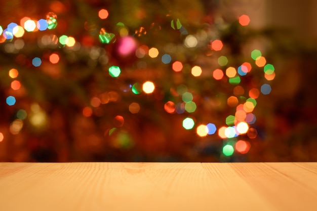 Vacances de Noël avec une table de bureau en bois vide sur un arbre de Noël décoré