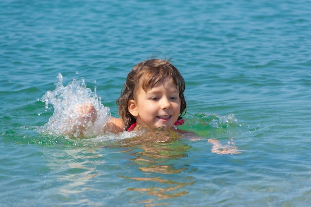 Vacances à la plage, enfant heureux éclaboussant dans la mer