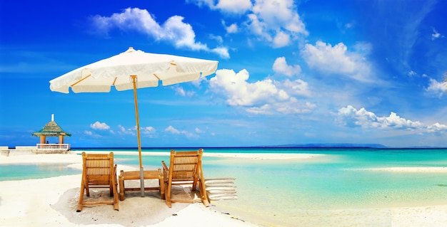 Vacances tropicales relaxantes, parasol avec deux chaises de plage sur la plage de sable blanc