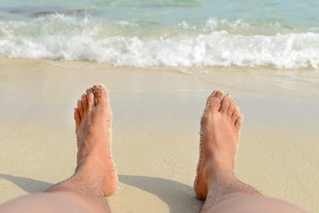 Vacances de vacances. Homme pieds nus relaxant sur la plage. Texture vague et sable.