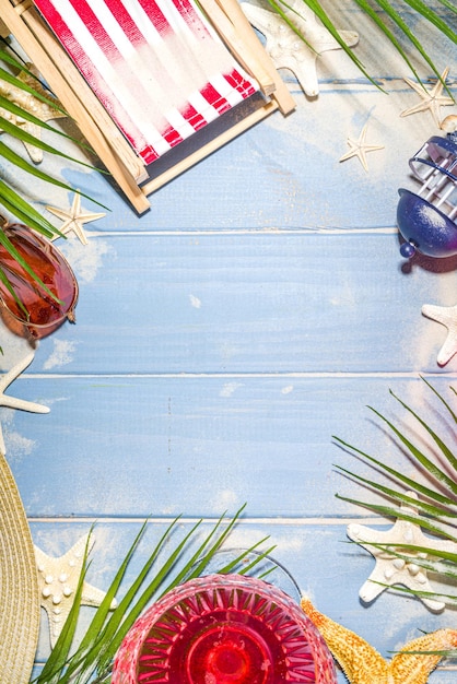 Vacances de vacances à la plage d'été et fond de voyage avec chaise longue, bouée de sauvetage, cocktail, feuilles tropicales, sable, lunettes de soleil, étoiles de mer coquillages. Espace de copie de fond en bois éclairé par le soleil bleu