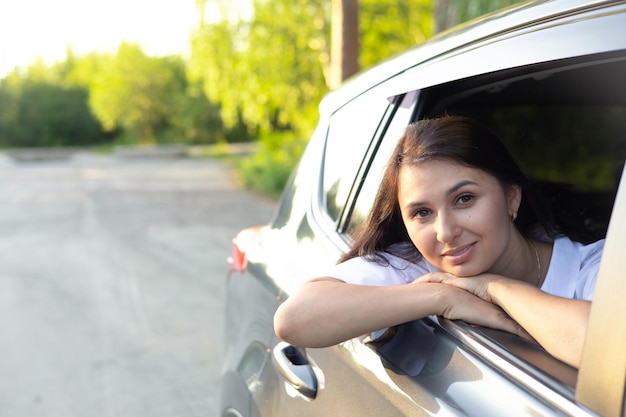 Vacances de voyage Une belle jeune femme est assise dans une voiture et sourit en regardant au loin