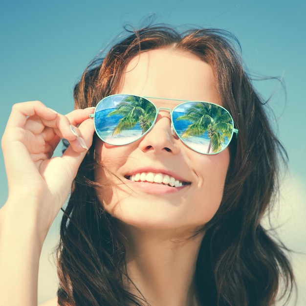 vacances, voyage, vacances et concept de bonheur - belle femme à lunettes de soleil avec réflexion sur la plage