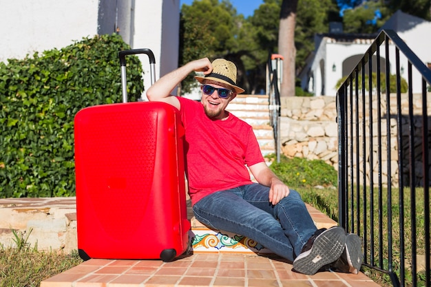 Vacances, voyages, concept de personnes. jeune homme assis dans les escaliers avec des valises.