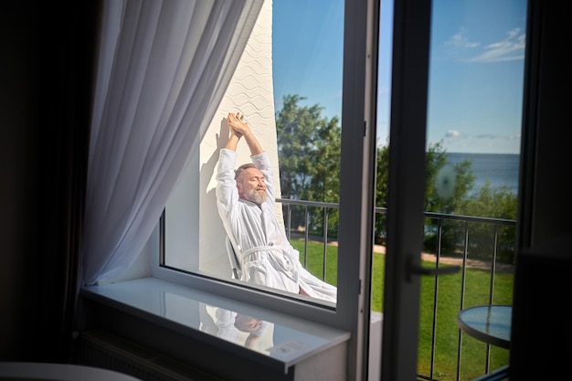 Vacancier dans le peignoir blanc se prélassant au soleil