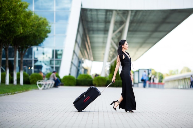 Vacation Une passagère souriante se dirige vers la porte de sortie en tirant une valise dans le hall de l'aéroport