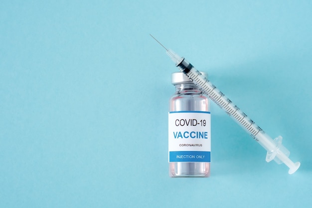 Vaccin contre le coronavirus et seringue sur fond bleu clair