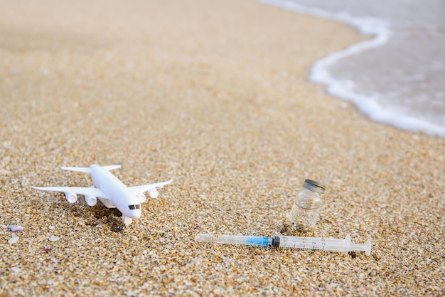 Vaccin contre Covid-19, seringue, avion sur la plage.