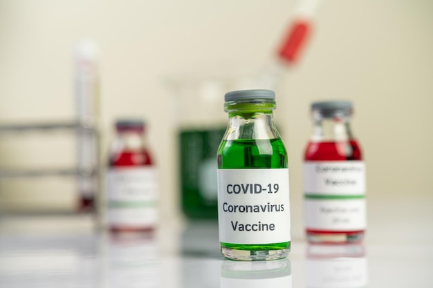 Photo le vaccin contre le covid19 est en rouge et vert dans des bouteilles placées sur le sol focus sélectif