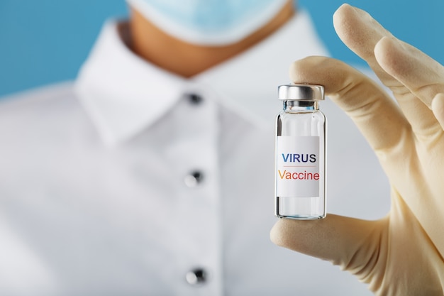 Vaccin contre le virus sur une ampoule entre les mains d'un médecin scientifique dans des gants en caoutchouc avec un vaccin