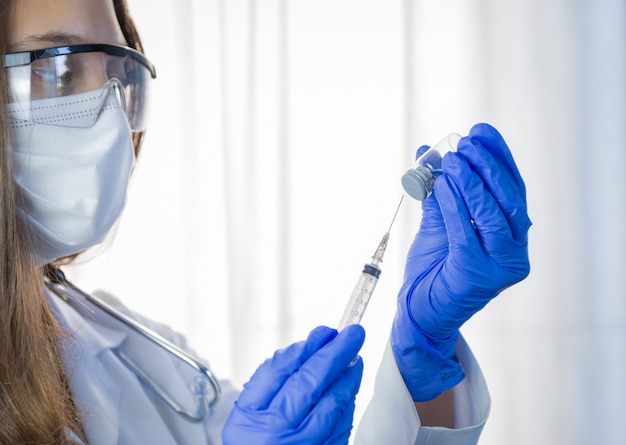 Vaccin entre les mains du chercheur, une femme médecin tient une seringue et une bouteille avec un vaccin pour guérir le coronavirus.