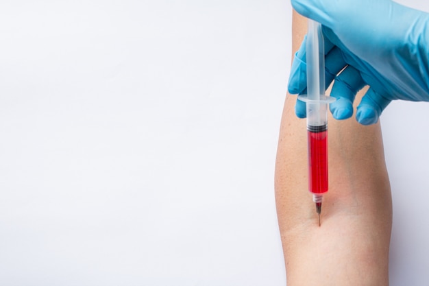 Vaccin rouge dans le bras avec mur blanc