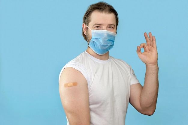 Vaccination réussie de Covid19 Homme vacciné faisant des gestes d'accord et montrant le bras avec l'aide de bandage