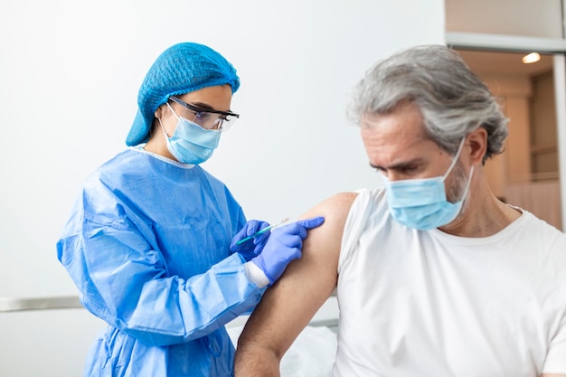 Vaccination vaccination concept de prévention des maladies Homme portant un masque médical recevant le vaccin Covid19 ou contre la grippe à l'hôpital Infirmière professionnelle ou médecin donnant une injection antivirale au patient