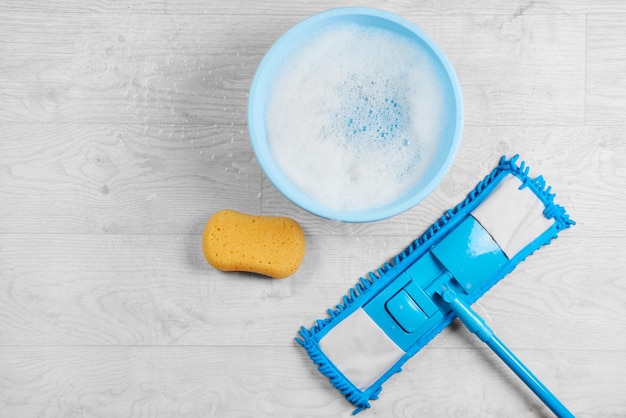 Vadrouille en microfibre humide bleue avec détergent Kit de désinfection de nettoyage sur un sol blanc isolé Concept d'entretien ménager