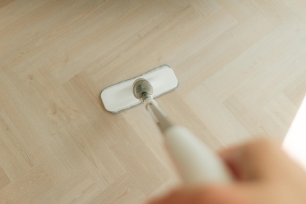 Vadrouille nettoyant la poussière sur le parquet de l'appartement