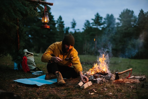 Un vagabond solitaire dîne dans les montagnes près d'un feu de camp