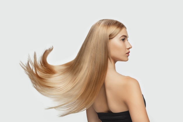 Vague Beau modèle avec de longs cheveux blonds volants lisses sur fond de studio blanc