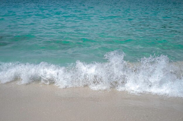 Vague côtière sur une plage de sable et l'eau bleue de l'océan