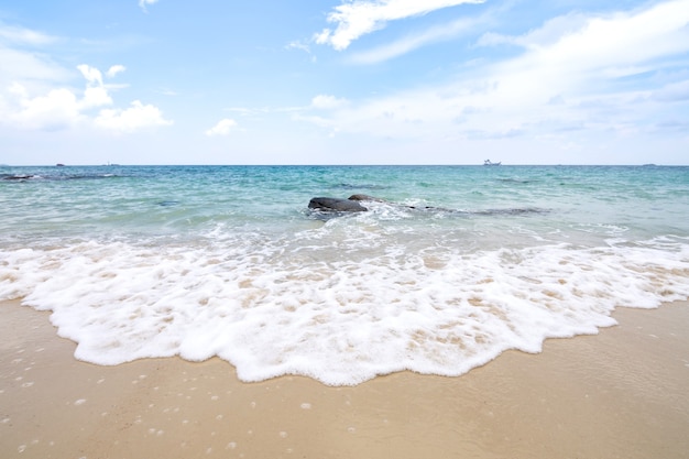 Vague douce de l'océan sur la plage de sable avec un ciel bleu.