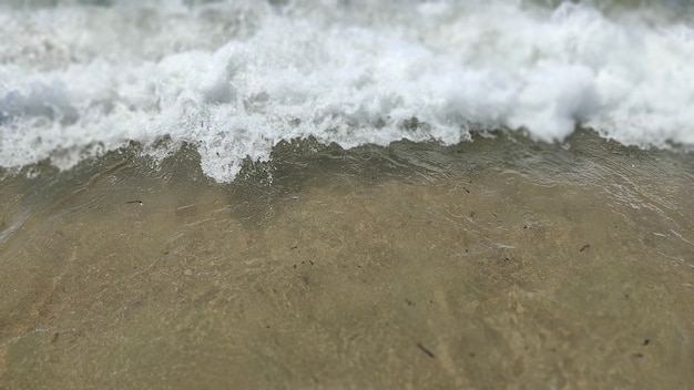 Vague de lumière sur le sable de la plage de la mer, gros plan