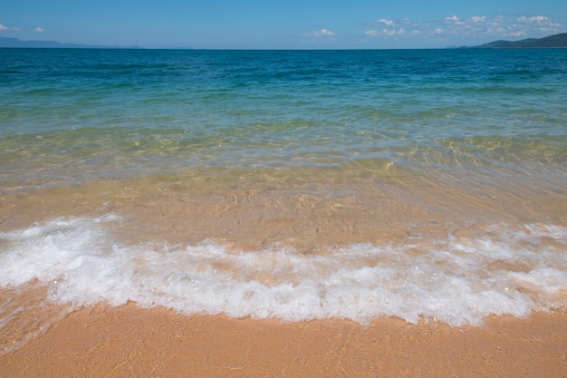 Vague de mer bleue sur la plage de sable. Contexte.