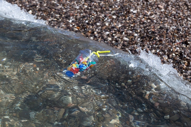 La vague de la mer jette des ordures en plastique jetables à terre Pollution des déchets ménagers en décomposition depuis la mer
