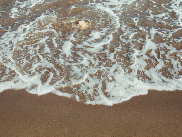 Vague de mer sur une pierre dans le sable doré de la plage de Tarragone Espagne Concept de plage naturelle