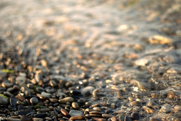 Une vague de mer transparente roule sur une plage de galets, loisirs et voyages, défocalisation, bokeh.