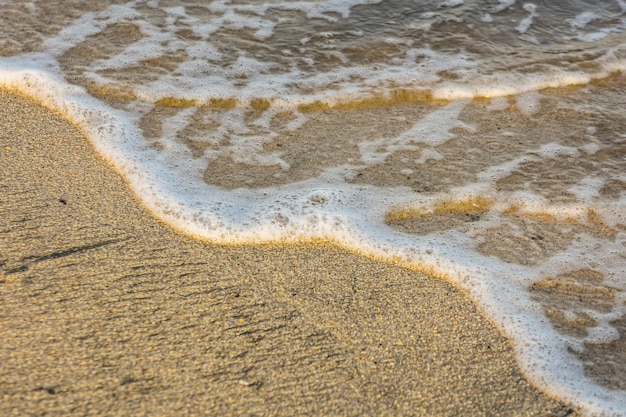 Vague avec de la mousse blanche sur la plage de sable en egypte vue détaillée