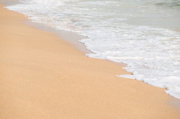 Photo vague de mousse douce et la mer sur le fond de la plage de sable