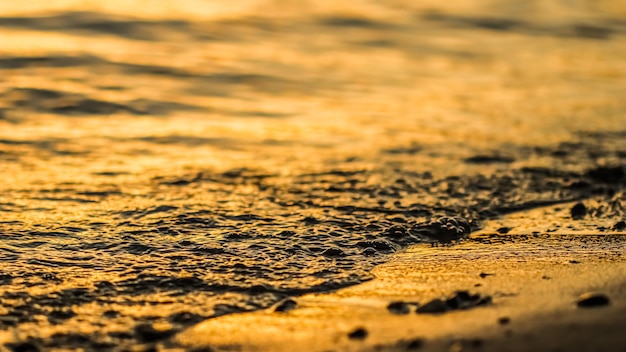 Vague qui coule sur la plage de sable de la mer au coucher du soleil Fond de vacances d'été et concept de nature côtière