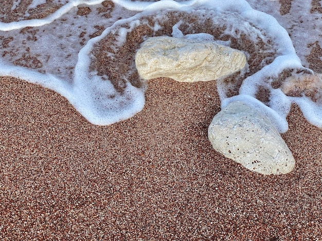 Une vague roule sur le sable et le sable est blanc.