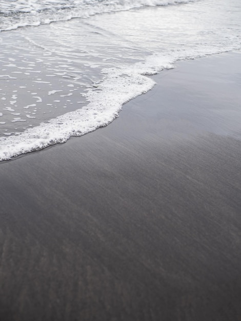 Vague volcanique de rivage de plage de sable foncé