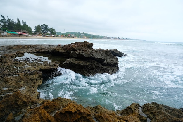 Les vagues au bord de la mer éclaboussent les rochers par une journée orageuse