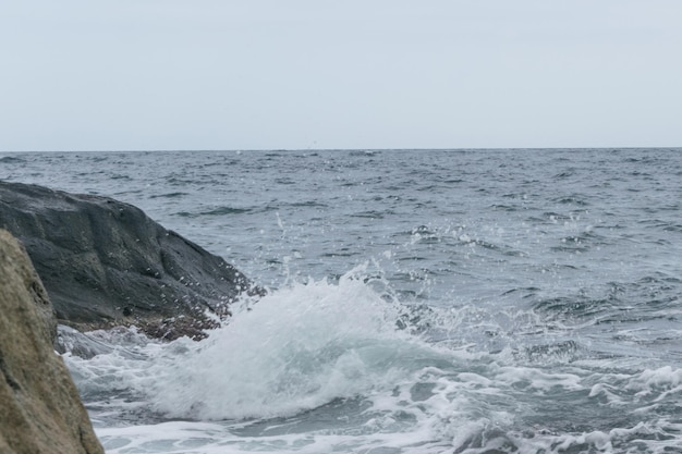 Les vagues battent contre les rochers au bord de la mer l'océan par temps nuageux