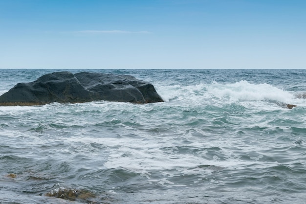 Les vagues battent contre les rochers au bord de la mer l'océan par temps nuageux