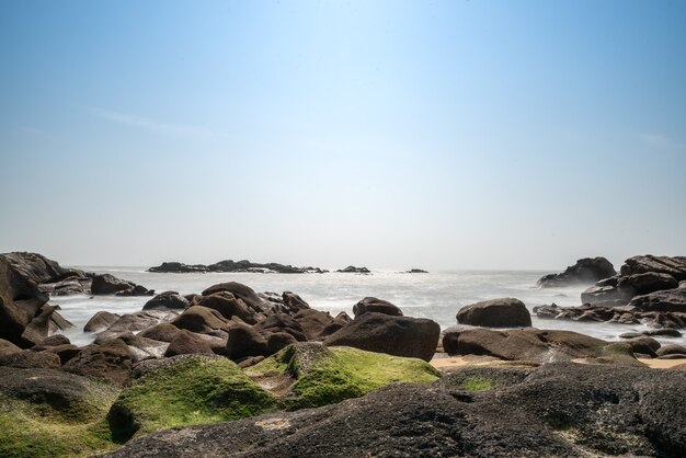 Les vagues blanches battent contre les rochers noirs