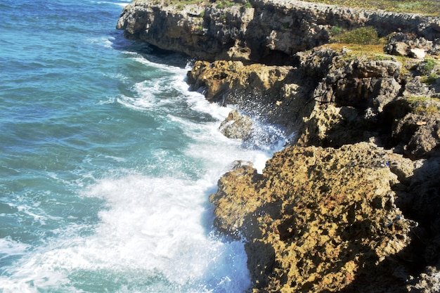 Les vagues bleues frappent les hautes falaises