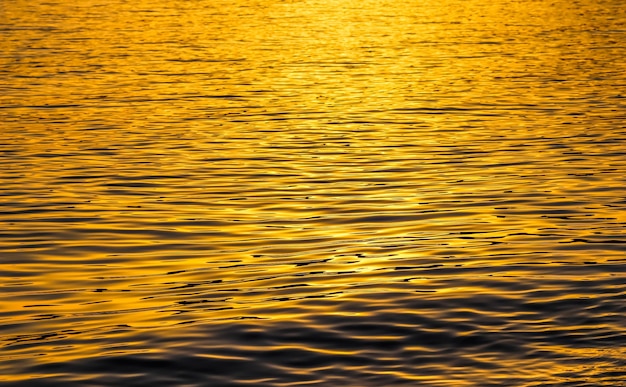 Photo les vagues dorées de la mer au coucher du soleil brillent comme arrière-plan de la surface concept de vacances d'été