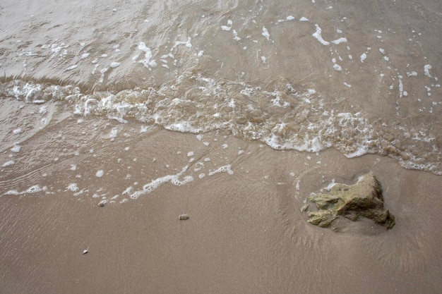 Photo des vagues d'eau de mer avec des bulles sur la plage