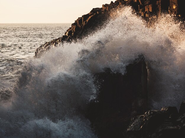 Les vagues éclaboussent sur les rochers du rivage.