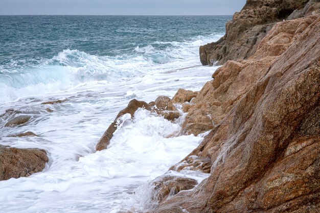 Les vagues écumantes de la mer se brisent sur les rochers côtiers. Paysage naturel marin