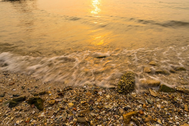 Photo vagues emportées sur le rivage au coucher du soleil avec